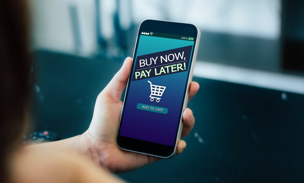 Buy Now Pay Later concept. Hand holding smartphone with Buy Now Pay Later message and shopping cart