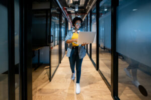Woman working in tech walking while holding laptop